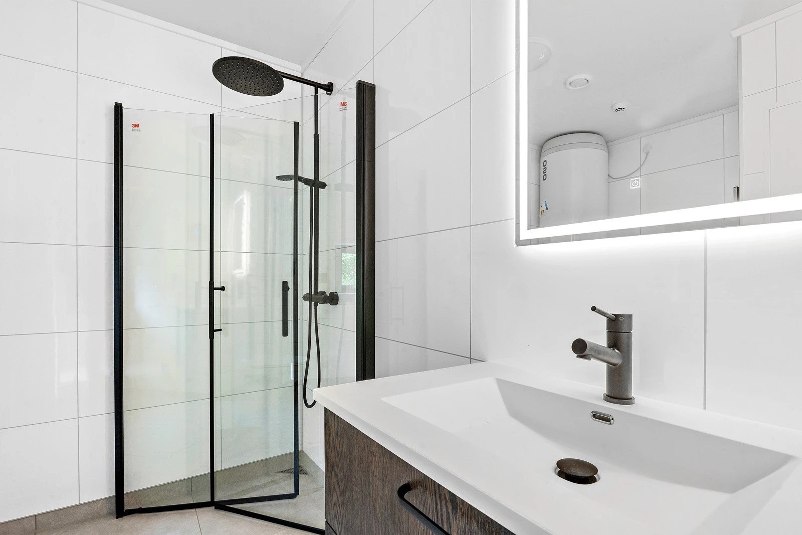 Bad/vaskerom i underetasjen med flislagt golv og svarte detaljar Galleribilde