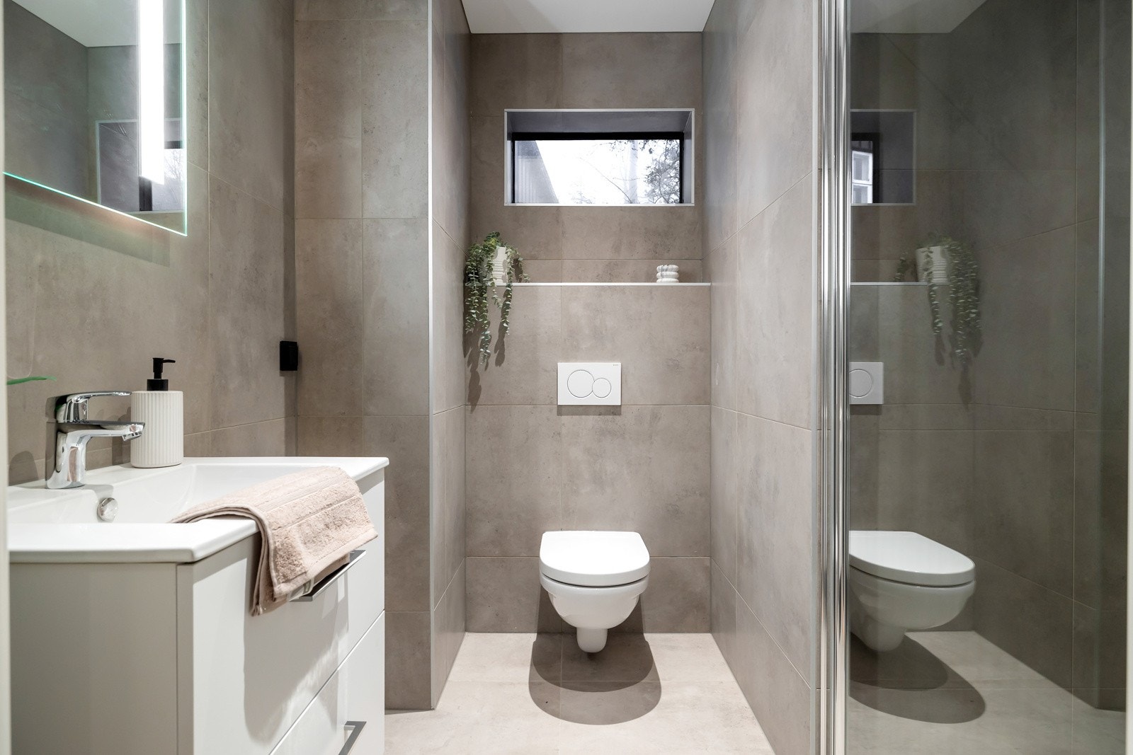 Bad 2. Begge badene er utstyrt med en servantinnredning med oppbevaring, toalett og en dusj med innfellbare glassfører. Galleribilde