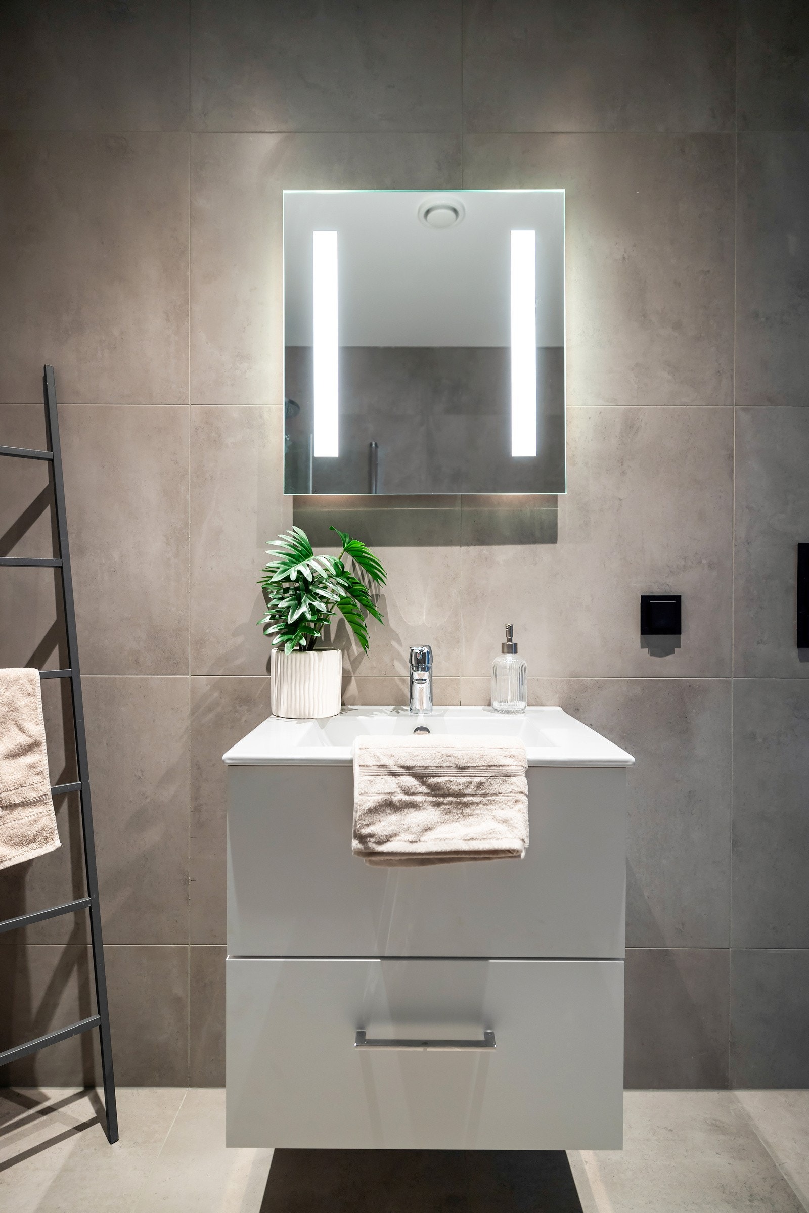 Badet er innredet med vegghengt servant med oppbevaring under og et speil med lys. Galleribilde