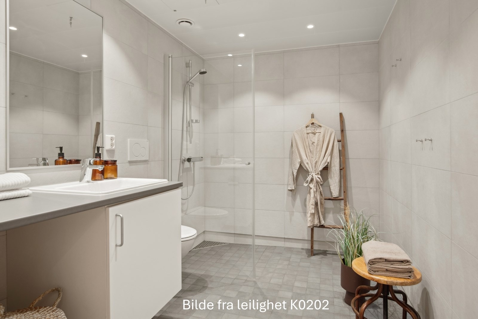 Romslig flislagt bad m/varmekabler, med minimalistiske fliser og downlights i tak Galleribilde