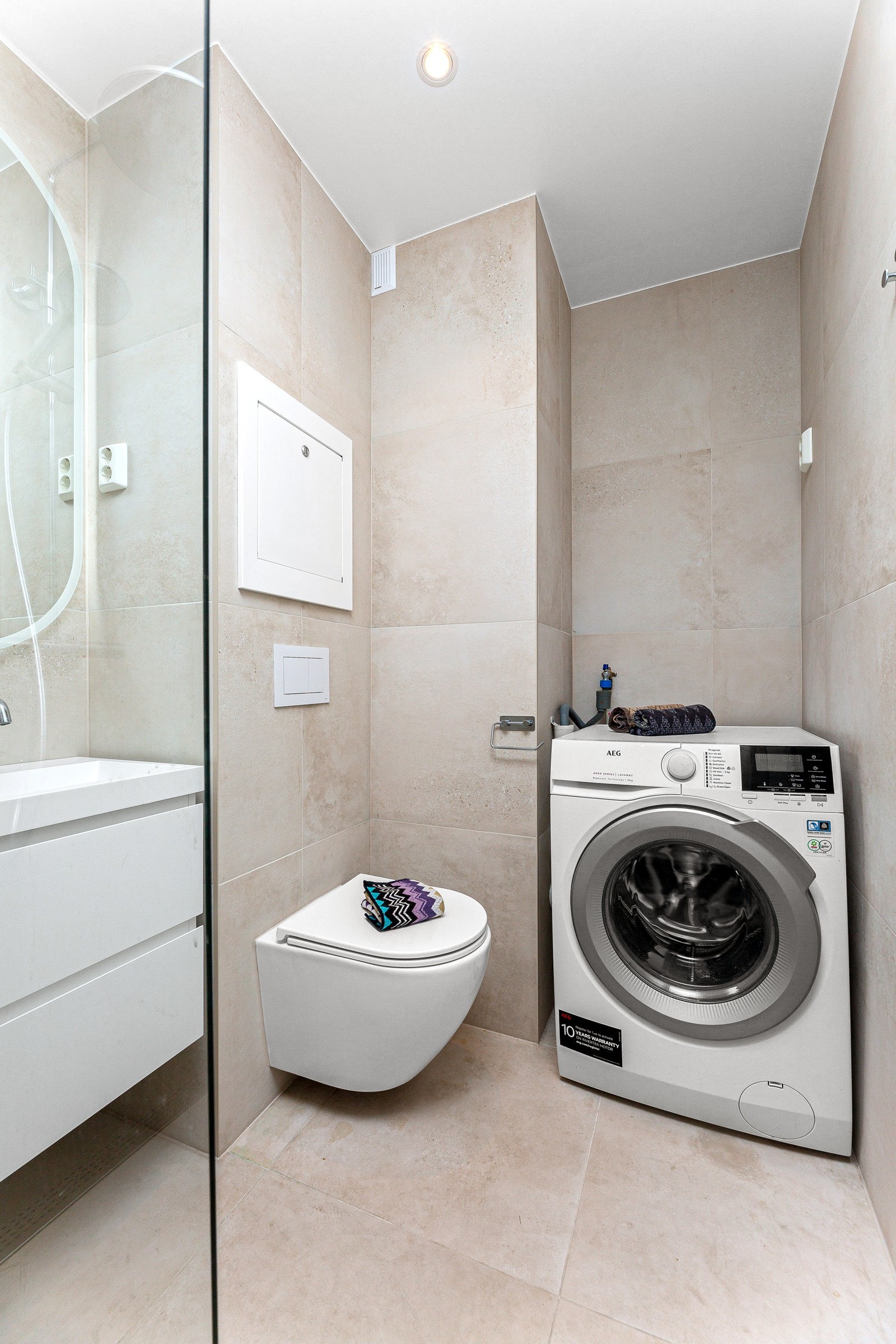 Badet inneholder servantskap med glatte fronter med speil og lysarmatur over, veggmontert wc, dusjsone med svingbare glassvegger og regnfallsdusj. Galleribilde