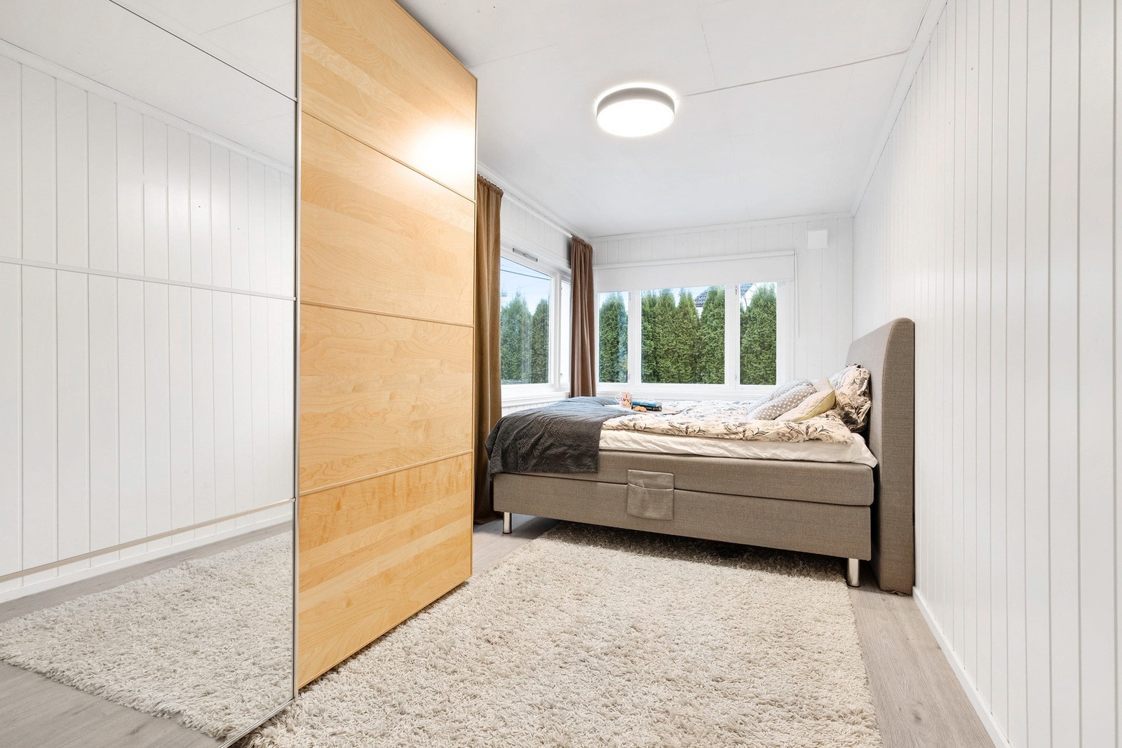 Lyst hovedsoverom med store vindusflater og fin plass til dobbeltseng og annet møblement Galleribilde