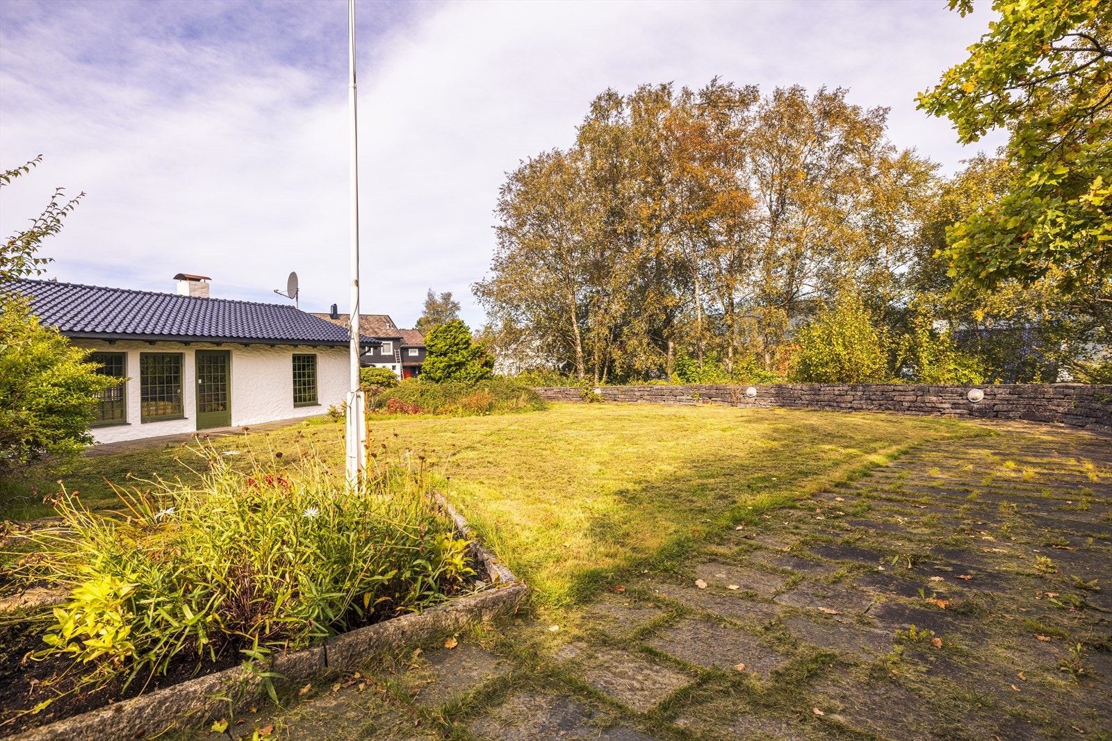 Tomten er pent opparbeidet med brostein, natursteinmurer, blomsterbed, stor plen, flotte prydbusker og trapper av skifter og granitt. Galleribilde