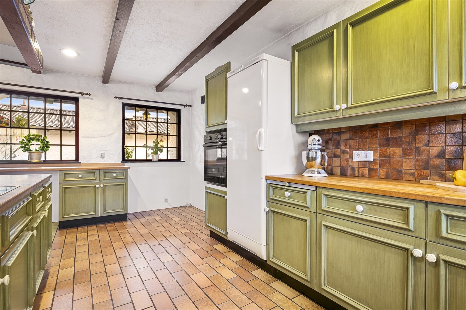 Også kjøkkenet har en kontinental stil med bjelker i taket, innfelte lys og fliset på gulvet. Galleribilde