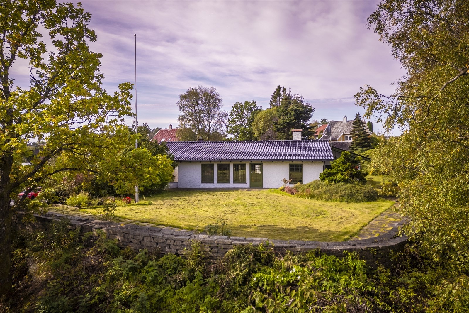 Boligen ligger skjermet på en høyde med store murer rundt hagepartiet. Galleribilde