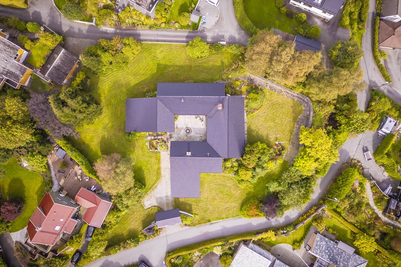 Eiendommen måler hele 4 834 kvm og tomten er pent opparbeidet med brostein, natursteinmurer, blomsterbed, stor plen, flotte prydbusker og trapper av skifter og granitt. Galleribilde