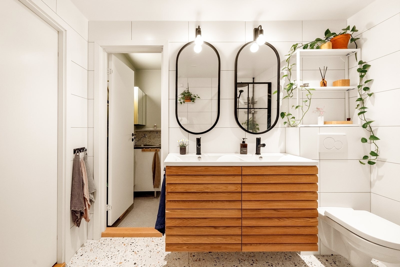 Badet er utstyrt med vegghengt toalett, dusjhjørne, badekar og møblement med dobbel servant. Galleribilde