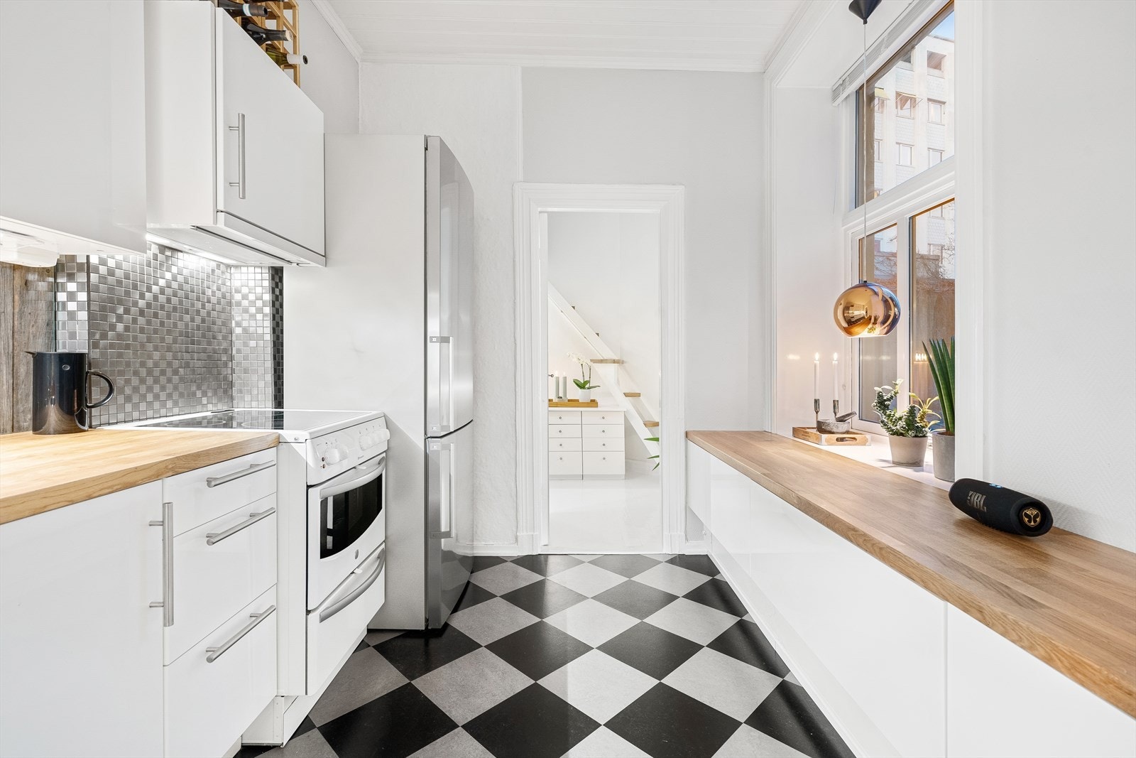 Innredning med mekanisk avtrekksvifte over stekesonen, komfyr, kombiskap og opplegg for vaskemaskin Galleribilde