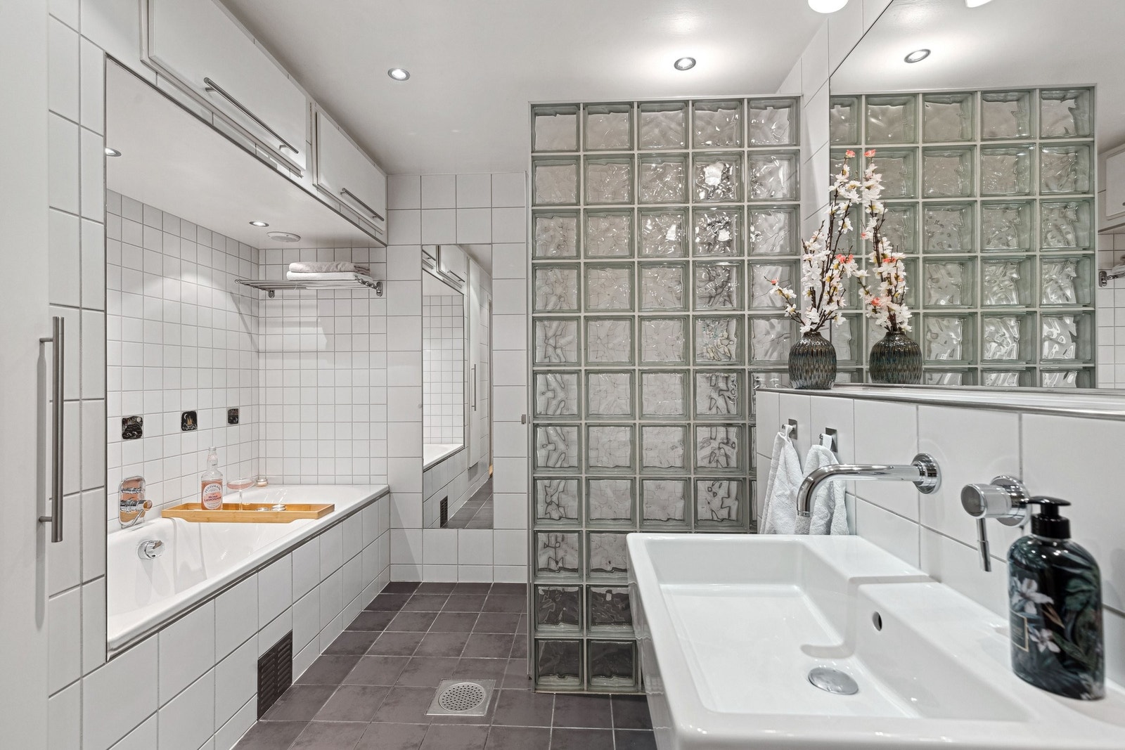Badet ligger i underetasjen og har et stort areal med grå gulvfliser i kombinasjon til hvite veggfliser. Galleribilde