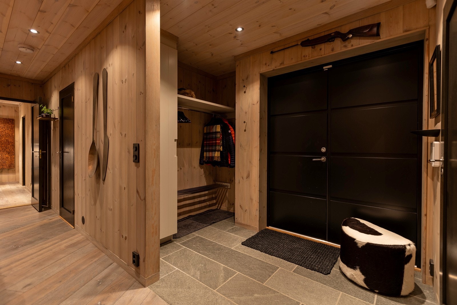 Man ankommer hytta via doble inngangsdører og inn til entreen hvor man kan henge fra seg yttertøyet og skoene kan tørke på det skiferbelagte varme gulvet. Galleribilde