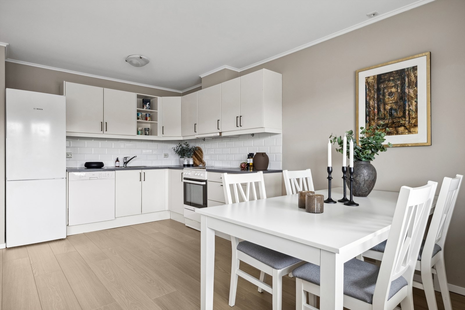 Kjøkkeninnredning av merket Sigdal. Innredningen har lyse slette fronter. Laminerte benkeplater med nedfelt oppvaskkum i rustfritt stål, ett-greps vannkran. Galleribilde