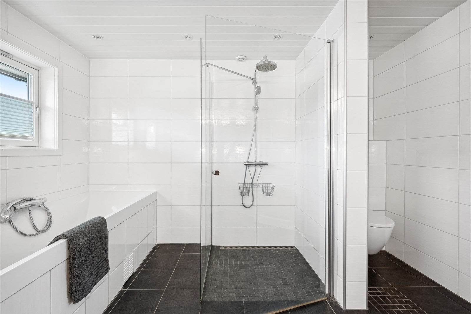 Baderommet er innredet baderomsinnredning med dobbel servant, badekar, dusjhjørne med dusjvegger i glass og vegghengt toalett. Galleribilde