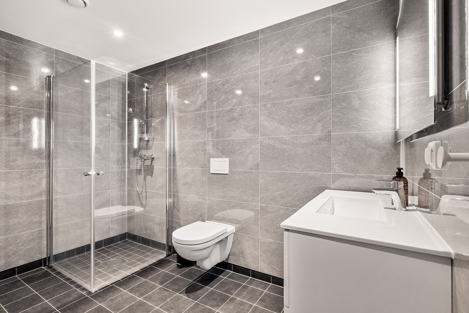 Badet har pene, grå fliser på gulv med underliggende elektriske varmekabler Galleribilde