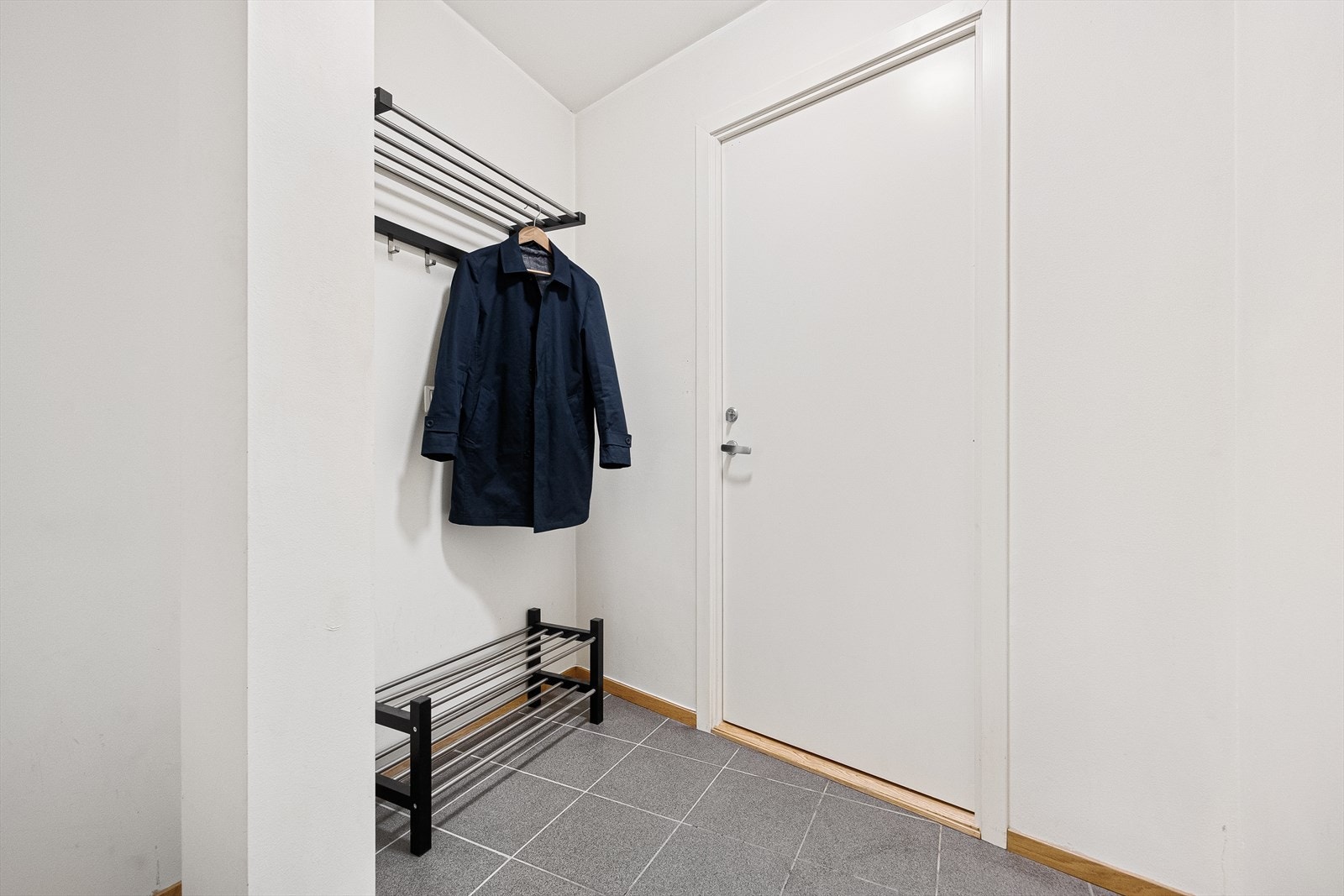 Leilighetens entré er lys og innbydende med plass til å henge fra seg ytterklær og plassere sko. Entréen har praktiske fliser på gulv og slette malte vegger. Galleribilde