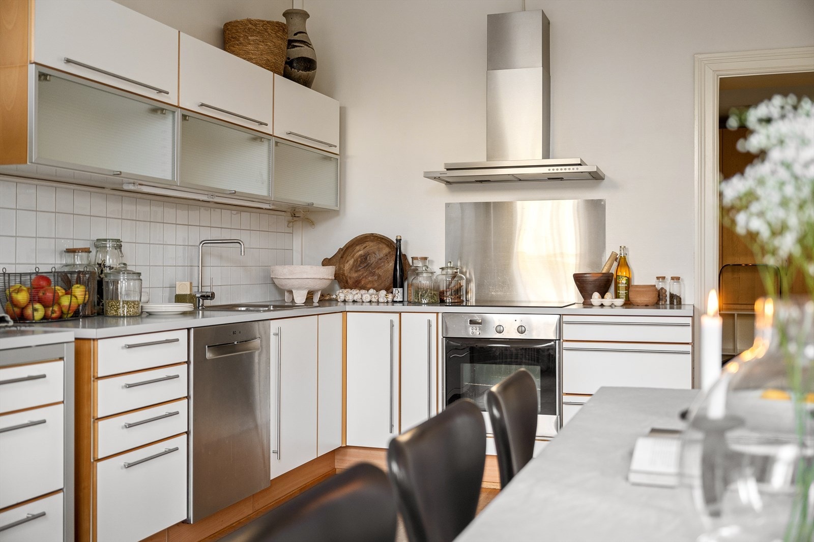 Laminat benkeplate med nedfelt kum i rustfritt stål samt veggmontert kullfilterventilator i stål - Induksjonstopp og stekeovn er integrert i innredningen Galleribilde