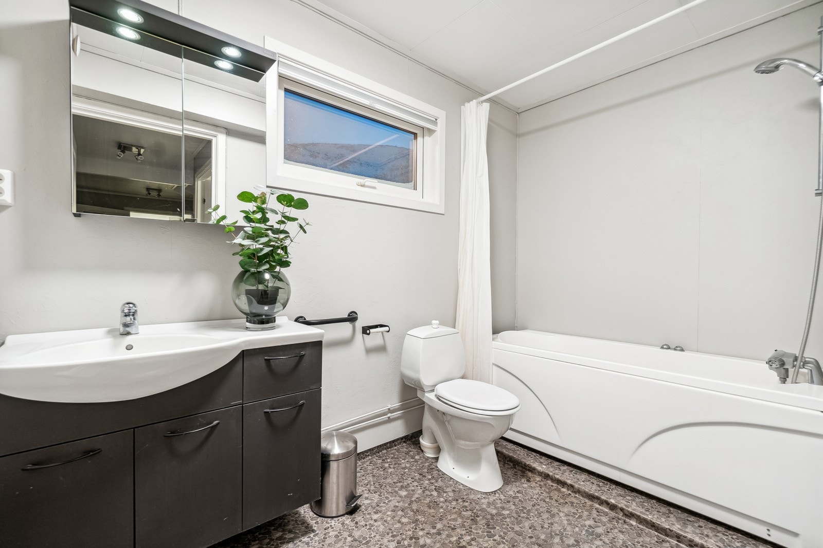 Boligens bad fremstår tidløst og har en praktisk plassering like ved soverommene i 1. etasje, og boligen har i tillegg et eget vaskerom. På badet finner du servantskap med tilhørende speilskap, badekar med dusjhode, og toalett. Galleribilde