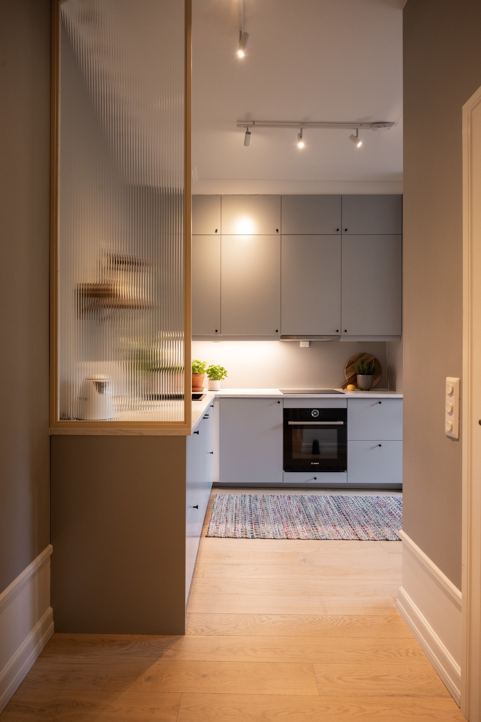 Rillet glassvegg fungerer som praktisk og pen romfordeler mellom kjøkken og gang. Galleribilde