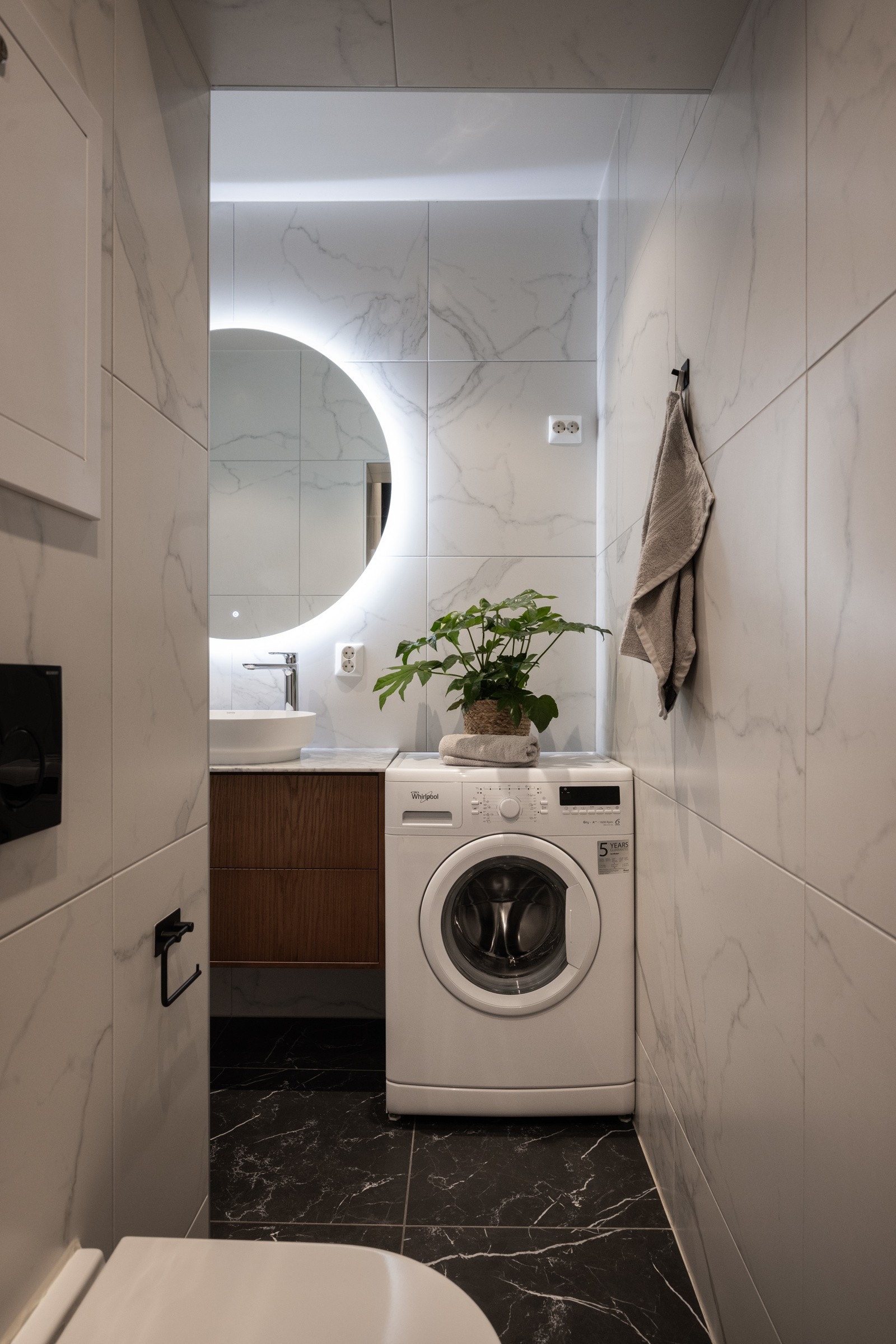 Badet er utstyrt med dusj, vegghengt toalett, servant med innredning og vegghengt speil med belysning. Opplegg for vaskemaskin. Galleribilde