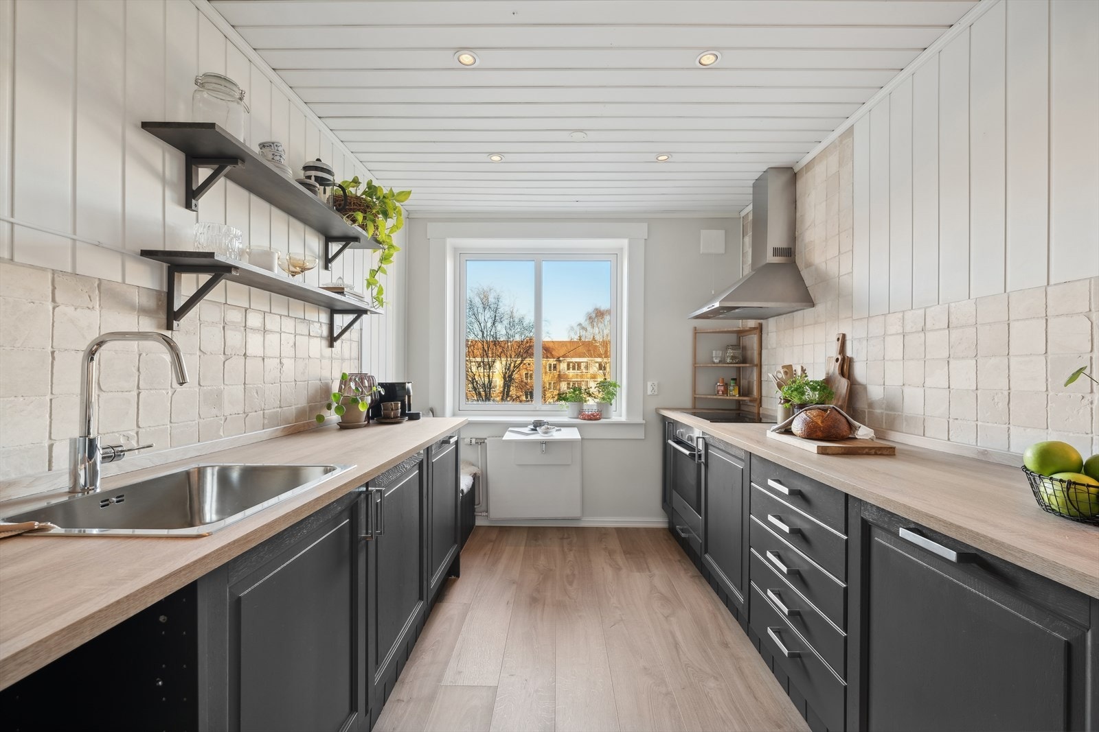 Flott kjøkken med benkeplass og lite frokostbord ved kjøkkenvinduet. Galleribilde