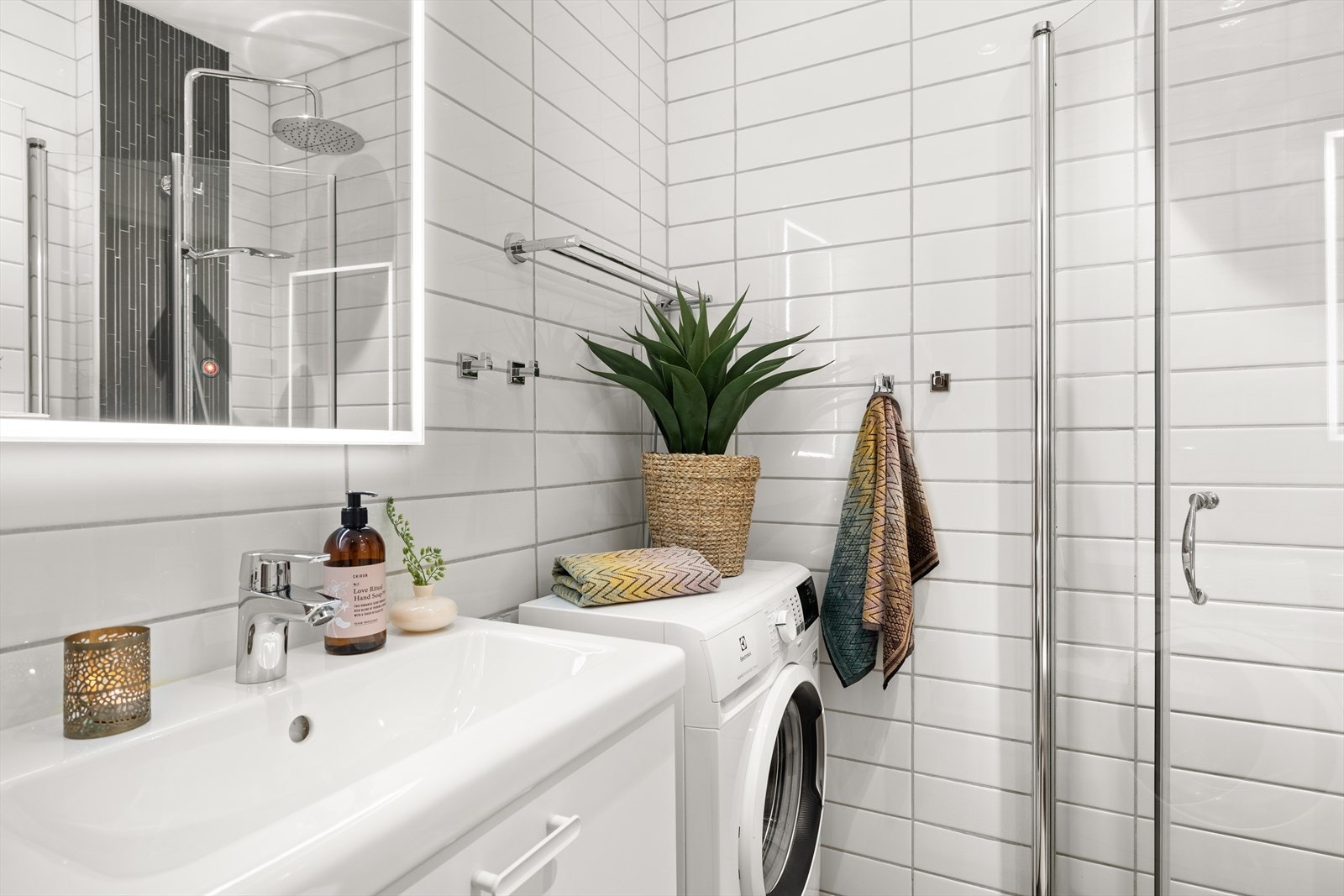 Dusj med svingbare dusjdører, veggmontert klosett, servant/servantskap, og opplegg for vaskemaskin (smal type). Galleribilde