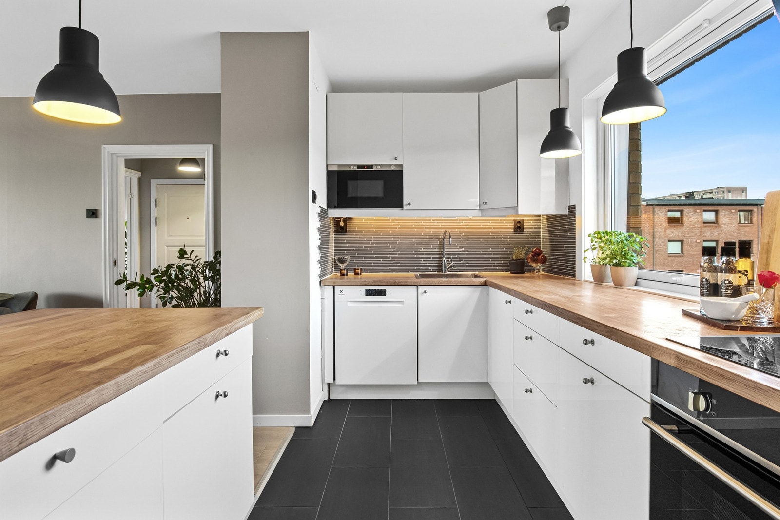 Her får man godt med skap- og benkeplass, Stilen er tidløs med slette, hvite fronter med dempefunksjon og benkeplater i heltre med nedfelt oppvaskkum og koketopp. Galleribilde