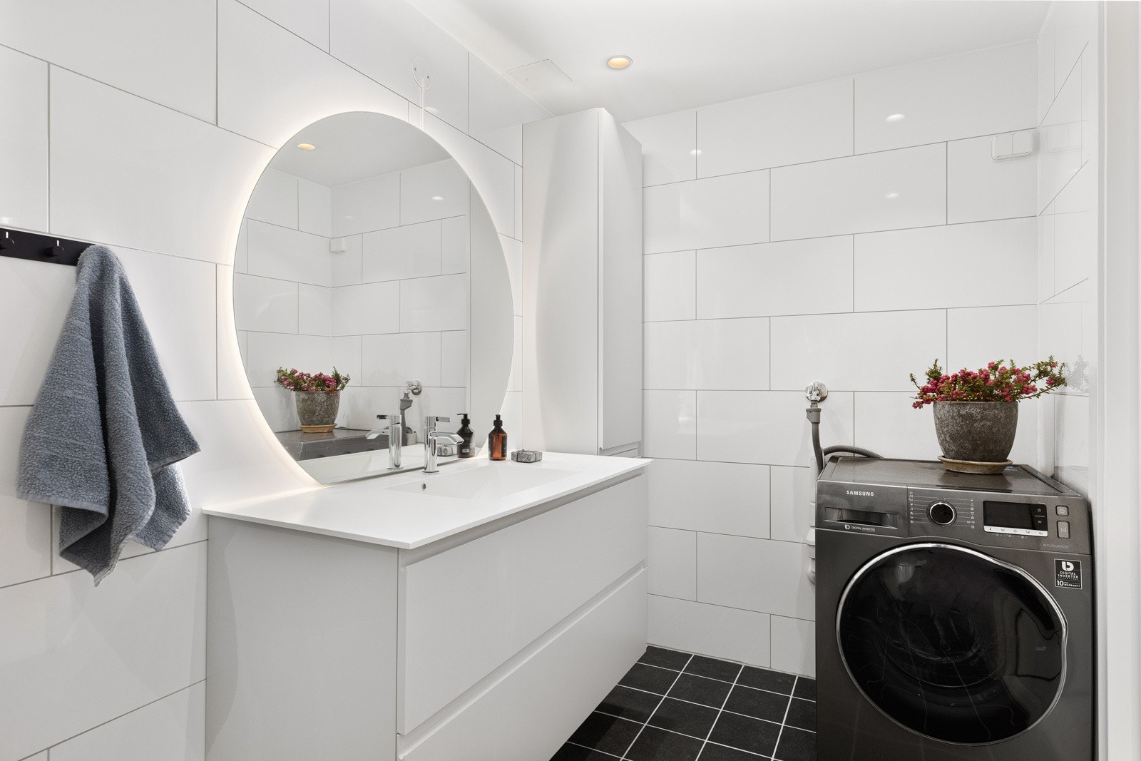 Baderomsinnredningen består av helstøpt servant over benkeskap med skuffer og et lekkert speil samt veggskap. Videre har badet dusjnisje med innfellbare dusjdører, vegghengt toalett og opplegg for vaskemaskin. Galleribilde