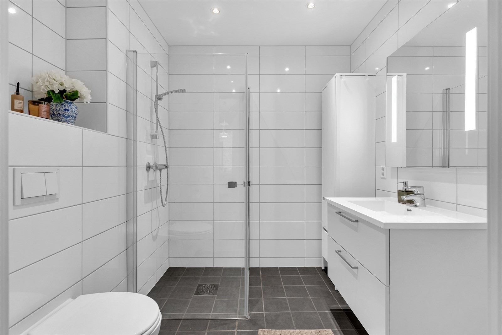 Badet i hybelen er bygget opp med flislagte gulv og vegger med vannbåren varme i gulvet. Videre er rommet utstyrt med dusj med glassdører, toalett og innredning med servant. Galleribilde