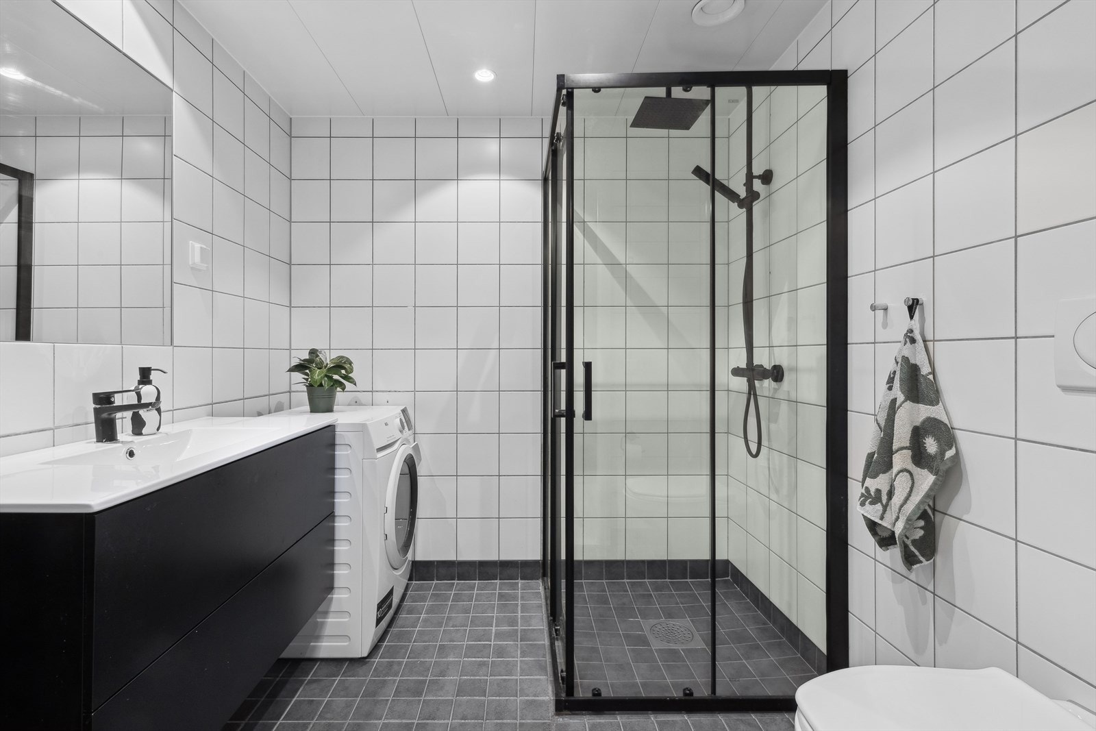 Romslig flislagt bad med gulvvarme og opplegg for vaskemaskin. Galleribilde