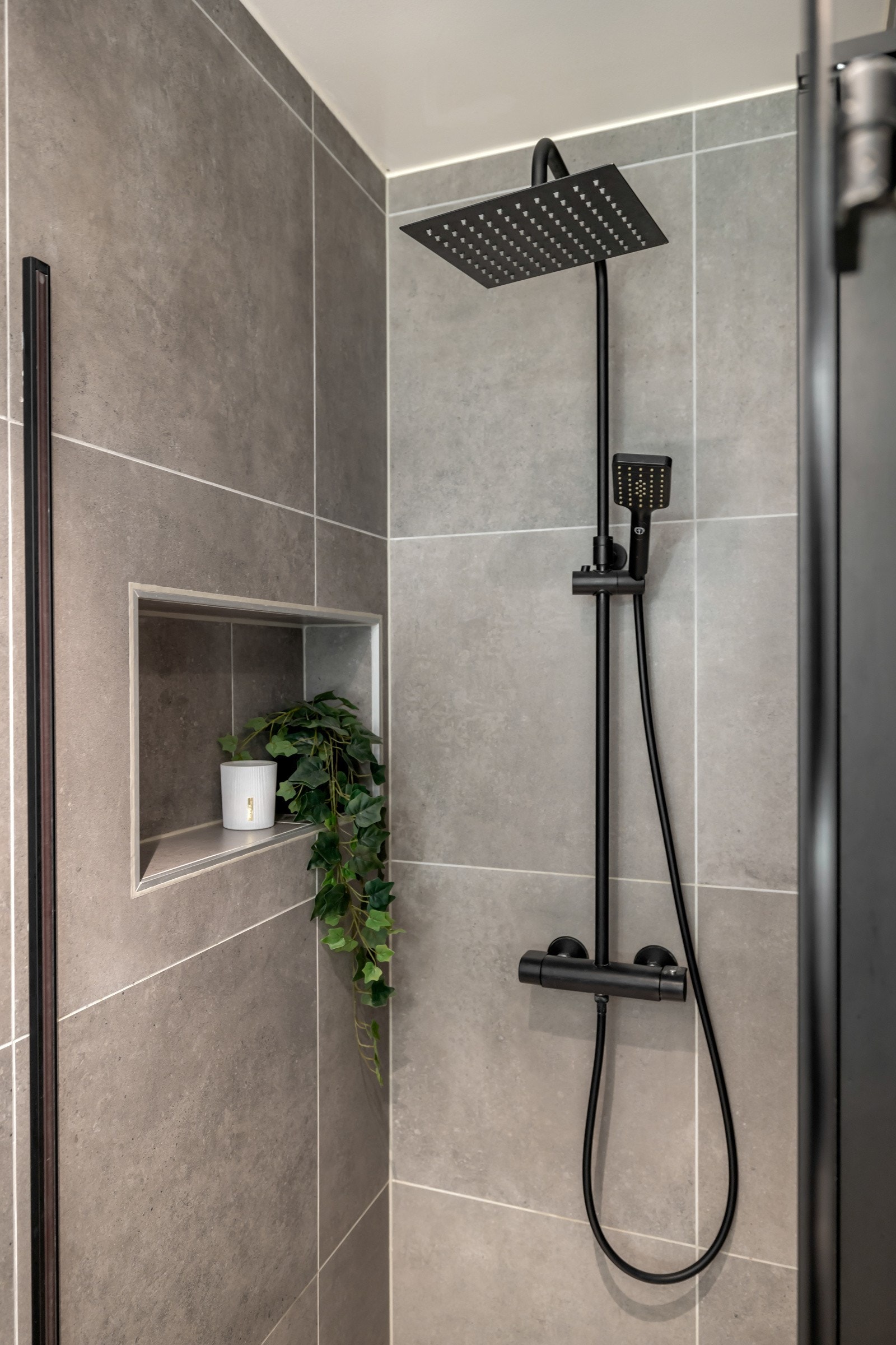 Romslig dujhjørne med praktisk nisje for oppbevaring av dusjprodukter. Galleribilde