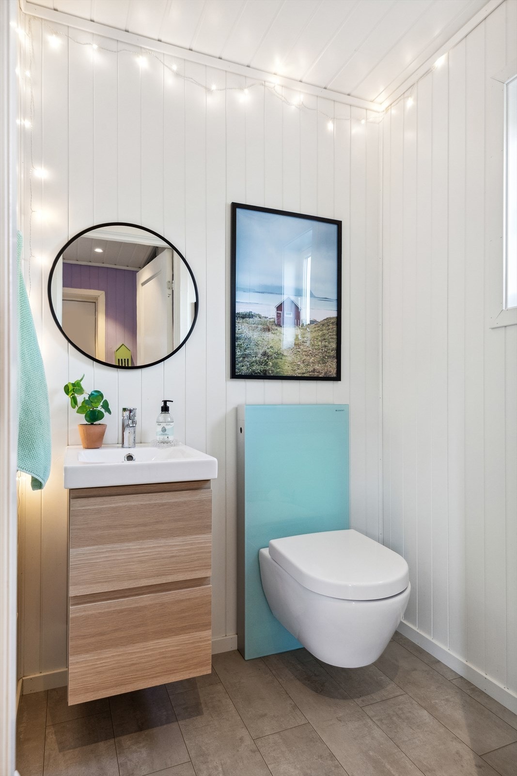 Toalettrommet har flislagt gulv, veggmontert toalett med waterguard og en stilren servantinnredning. Galleribilde