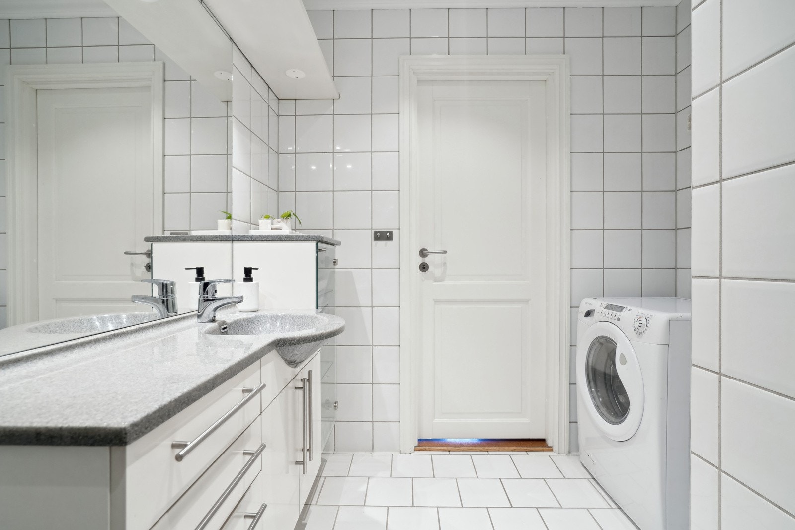 Badet er av god størrelse og har en stor baderomsinnredning med slette hvite dører, nedfelt servant og overliggende speil med belysning. Galleribilde