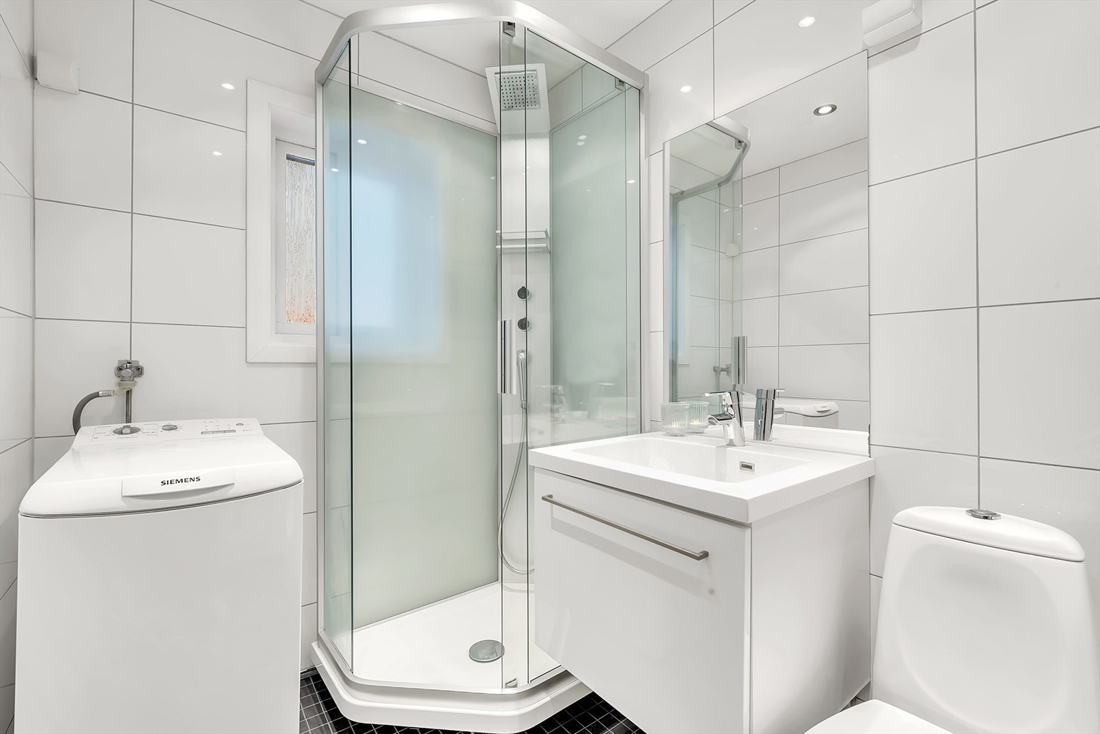 Innredningen består av dusjkabinett, servant med underskap, speil, plassbygget skap i vegg, wc, opplegg for vaskemaskin og varmekabler i gulv. Galleribilde