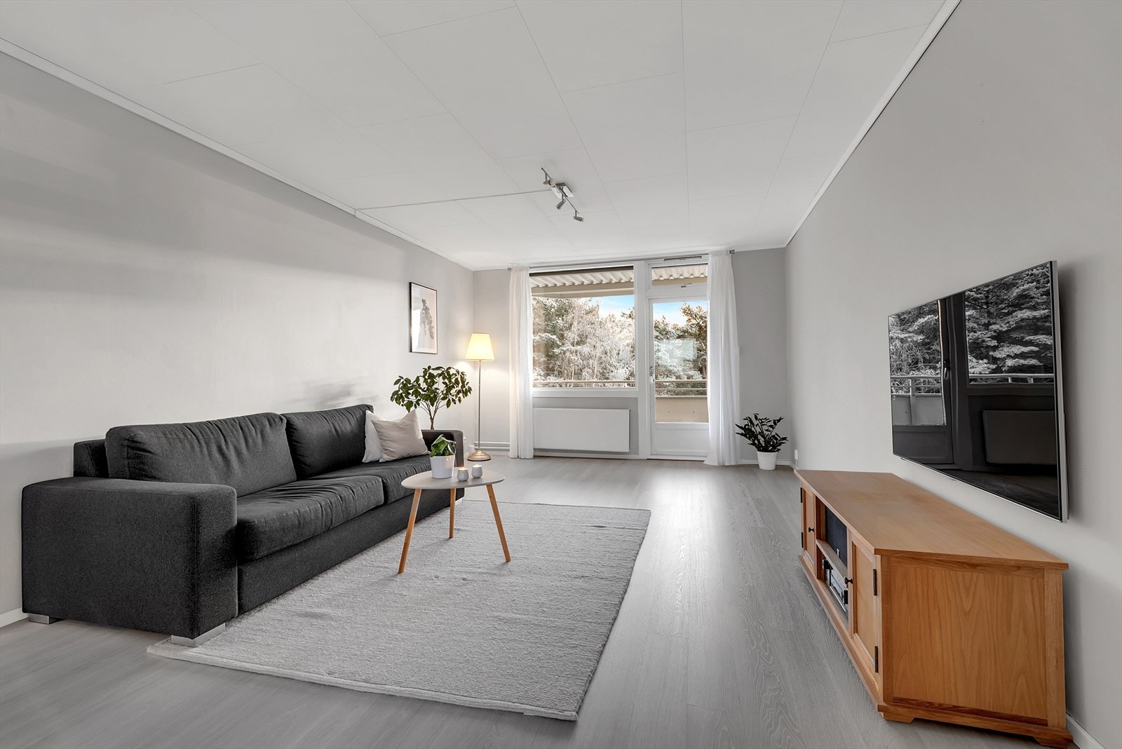 Lys og romslig stue med laminat på gulv, tapet på vegger og takessplater i tak. Her er det god plass for både sofagruppe samt spisemøblement. Galleribilde