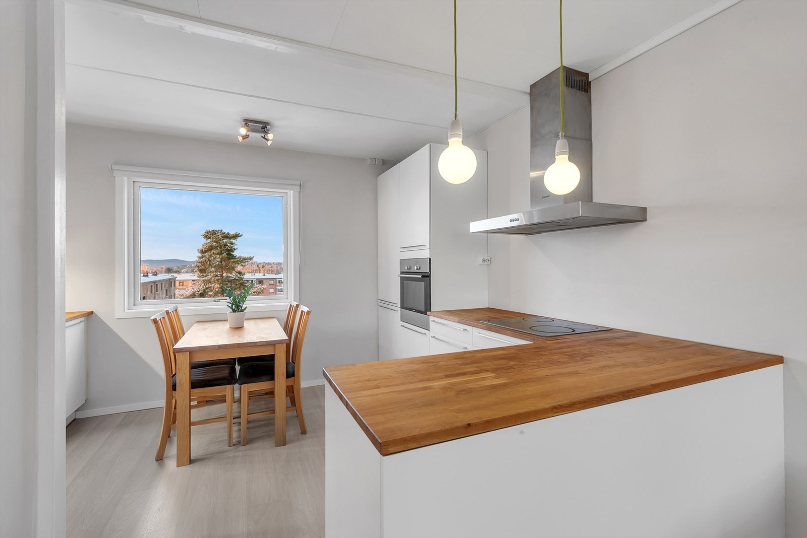 Kjøkkeninnredning med slette fronter, heltre eikebenkeplate, enkel oppvaskkum, ventilator og integrerte hvitevarer som stekeovn, koketopp, oppvaskmaskin og kjøl-/fryseskap. Galleribilde