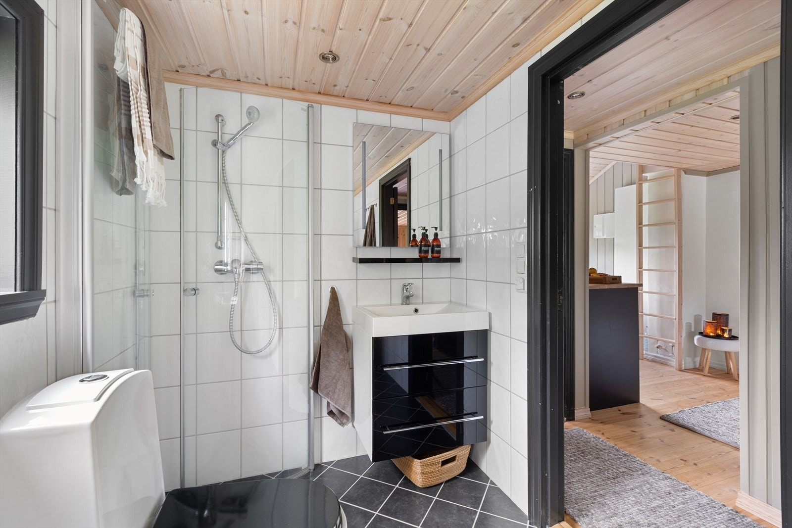 Helfliset baderom innredet med praktisk dusjhjørne, toalett, samt servant med skuffer og speil Galleribilde