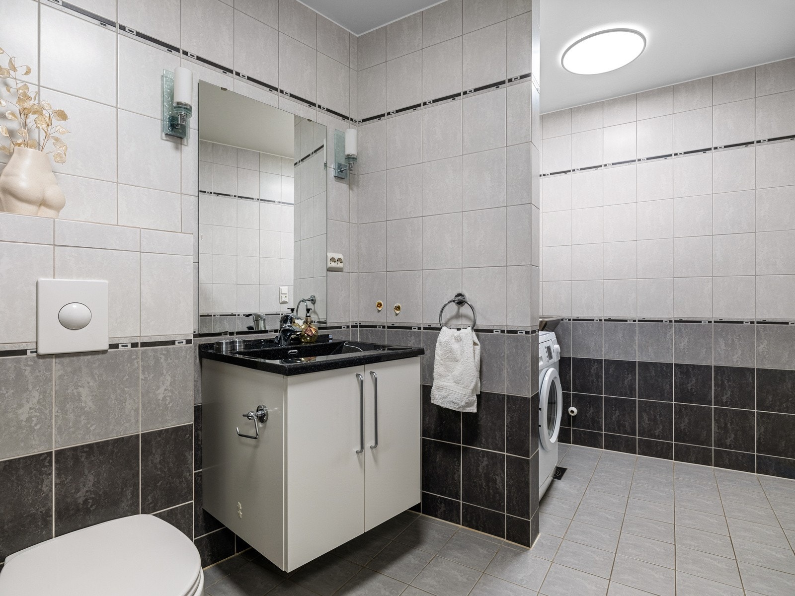 Baderomsinnredningen består av en heldekkende servant på en hvit skapseksjon, veggskap og speil. Galleribilde