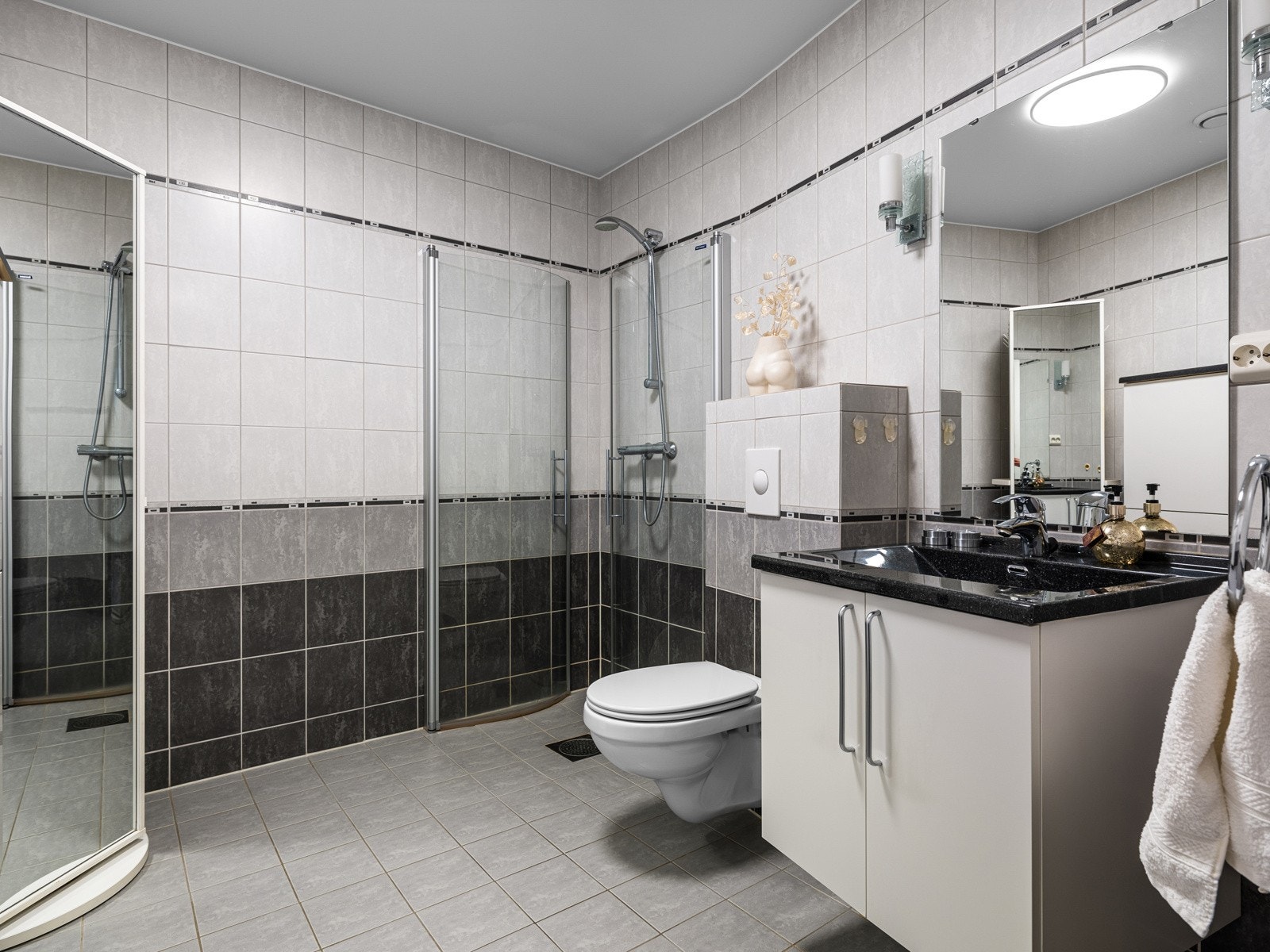 Badet er utstyrt med vegghengt toalett, opplegg til oppvaskmaskin, utslagsvask og dusjhjørne med innfellbare dusjdører i glass. Galleribilde