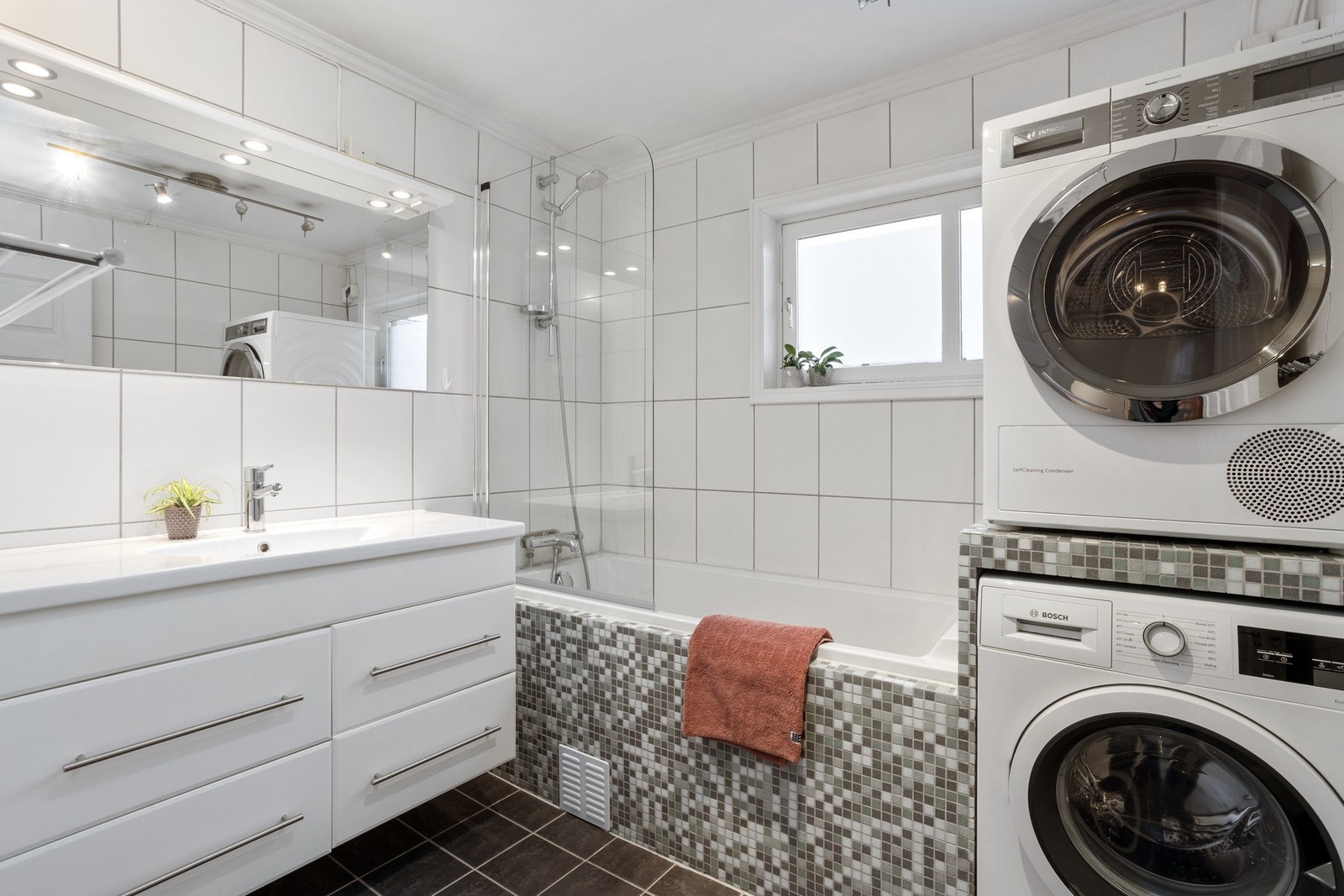 Pent flislagt bad med badekar og opplegg for vaskemaskin og tørketrommel. Galleribilde