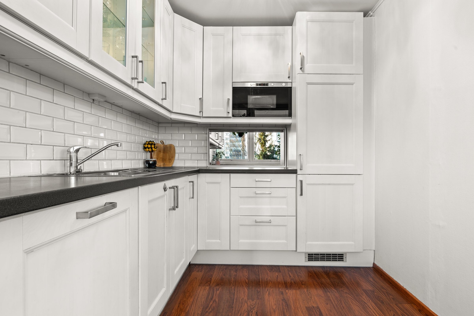 Hvitevarene en sømløst integrert i innredningen og består av induksjonstopp, stekeovn, mikrobølgeovn, oppvaskmaskin og kjøl/fryseskap Galleribilde