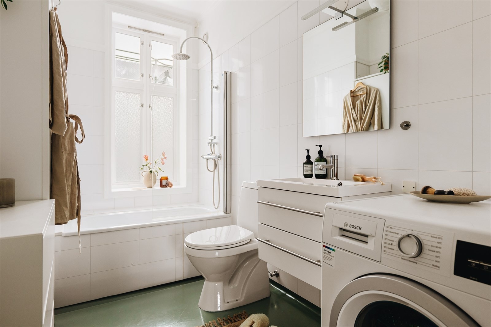 Badet er utstyrt med benkeskap med servant, badekar, gulvmontert toalett og opplegg for vaskemaskin. Galleribilde