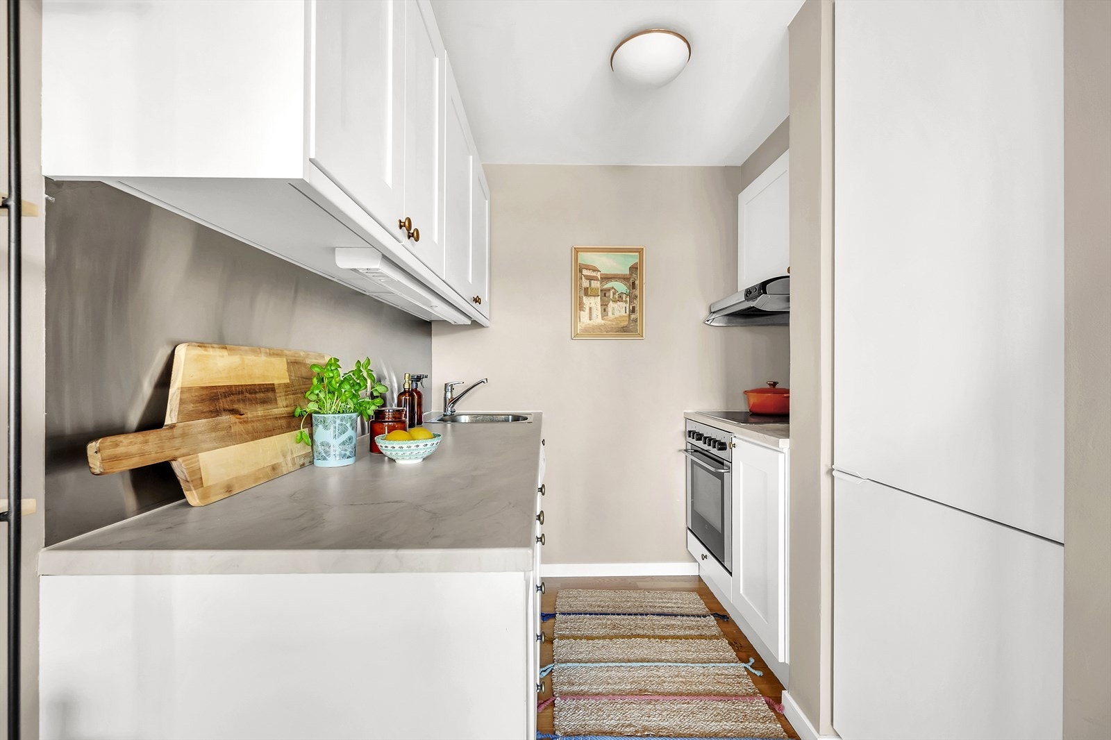 Kjøkkenet er innredet med god skap- og benkeplass, og har hvite kjøkkenfronter som harmonerer godt med fargene på stuen. Galleribilde