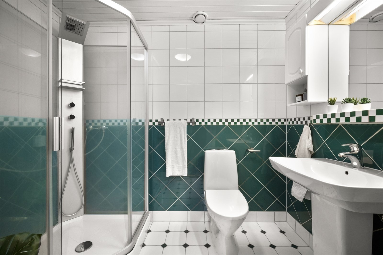 Flislagt bad med varmekabler i gulv. Badet har servant, toalett og dusjkabinett. Galleribilde
