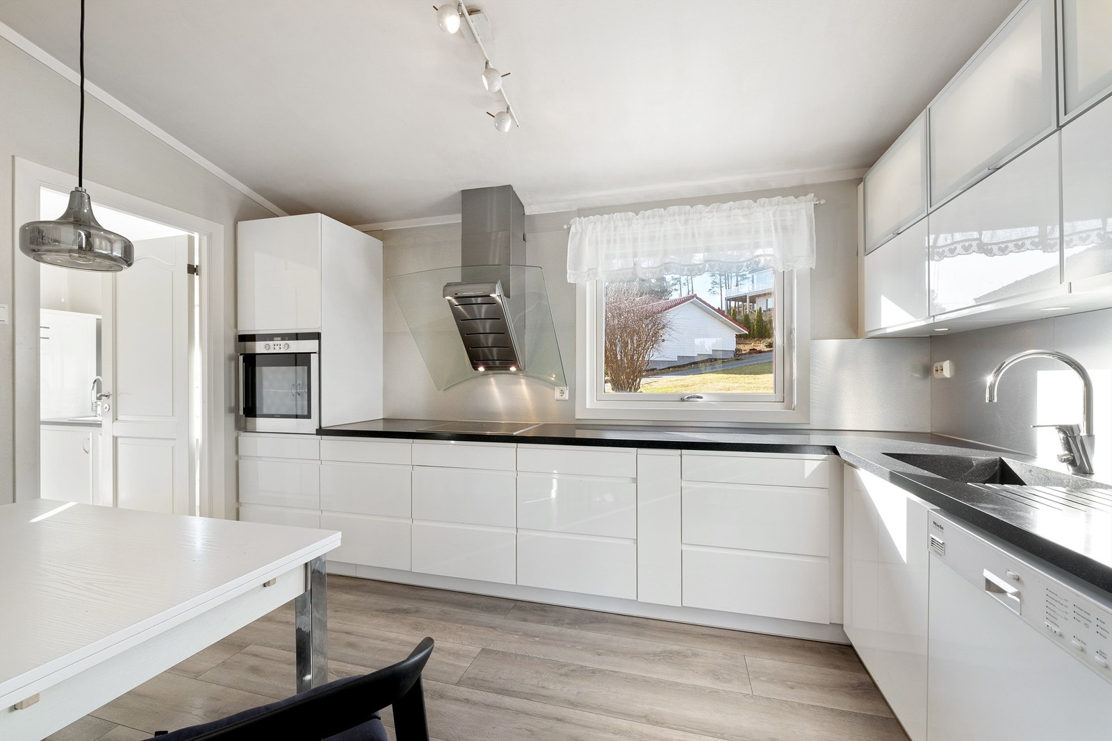 Hvit kjøkkeninnredning fra 2012 med Corian (kompositt) benkeplate med nedfelt oppvaskkum med ett-greps kjøkkenarmatur. Galleribilde