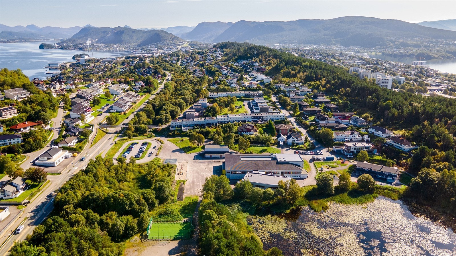 Dronebilde av nærområdet ved Lerstad Barneskole og Barnehage med Lerstadvannet i fremkant Galleribilde