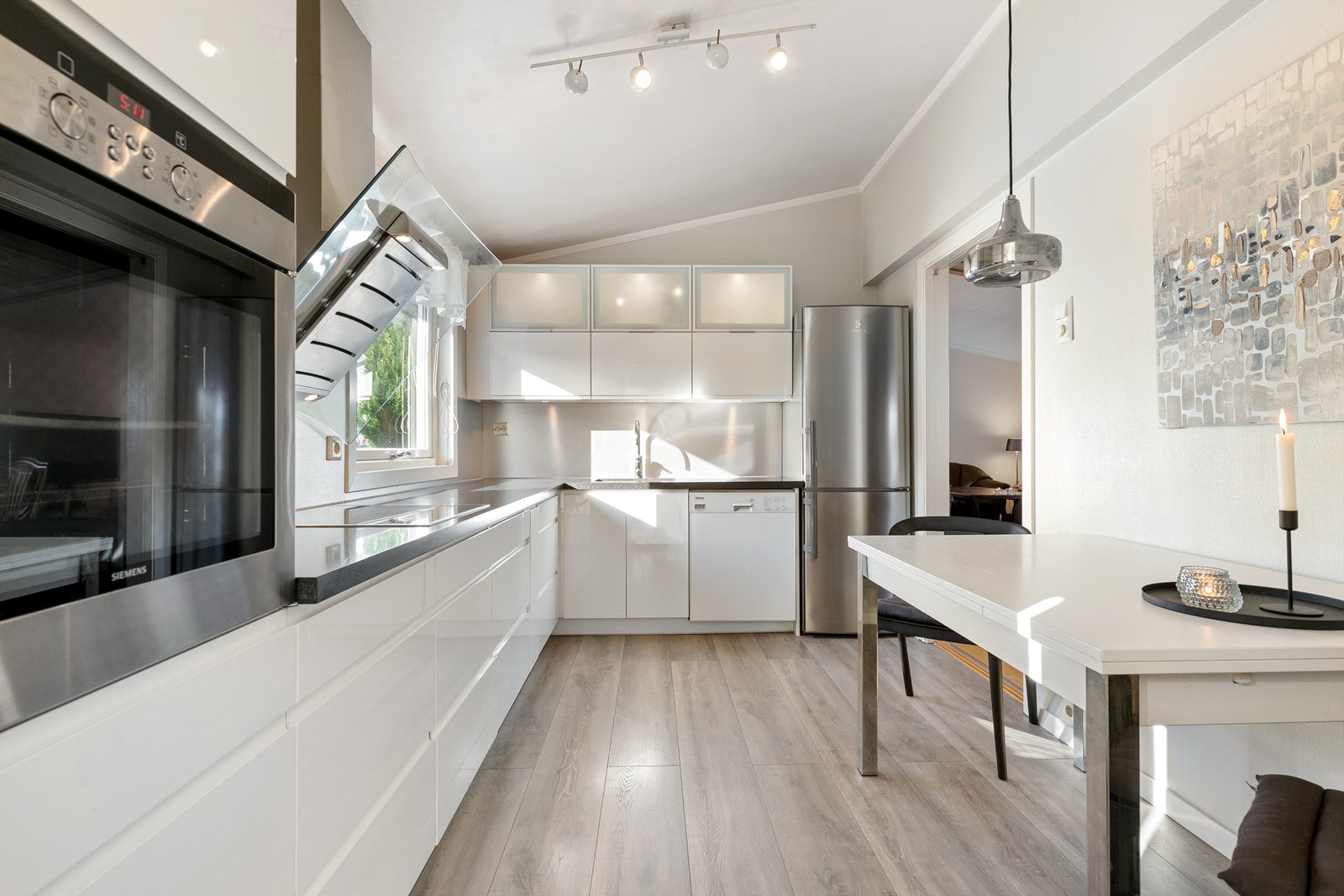 Nyere kjøkken med integrert stekeovn og platetopp på kjøkken. Frittstående oppvaskmaskin og kjøleskap med fryser. Vegghengt ventilator. Det er god plass til spisebord i kjøkken Galleribilde