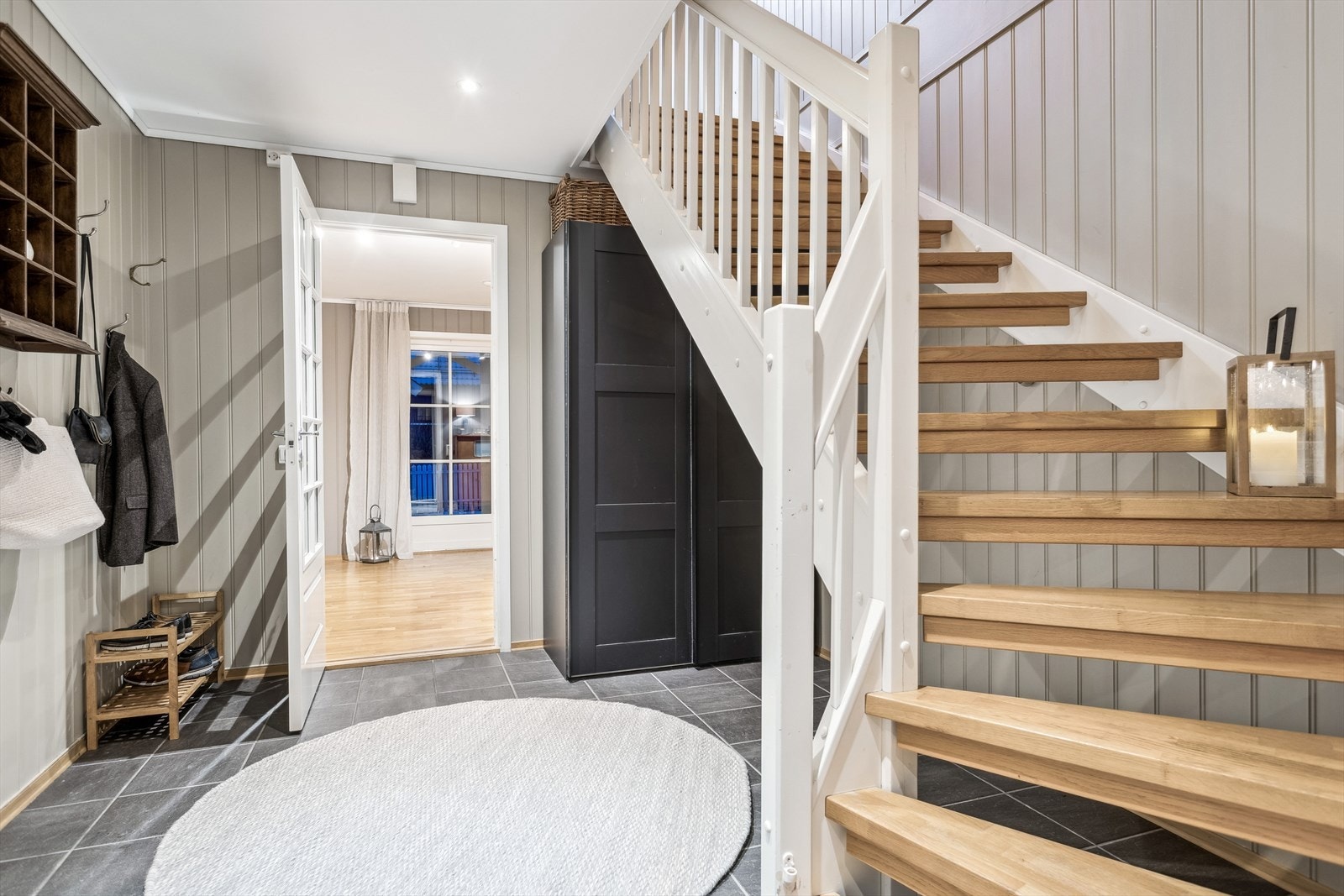 Man ønskes velkommen av en innbydende entré med flislagt gulv og skyvedørsgarderobe under trappa. Galleribilde