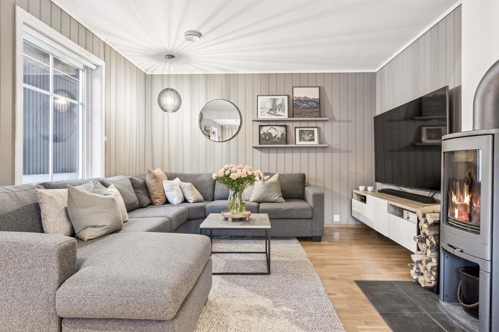Atmosfæren i stuen er lun og god, med både peisovn og gulvvarme montert. Galleribilde