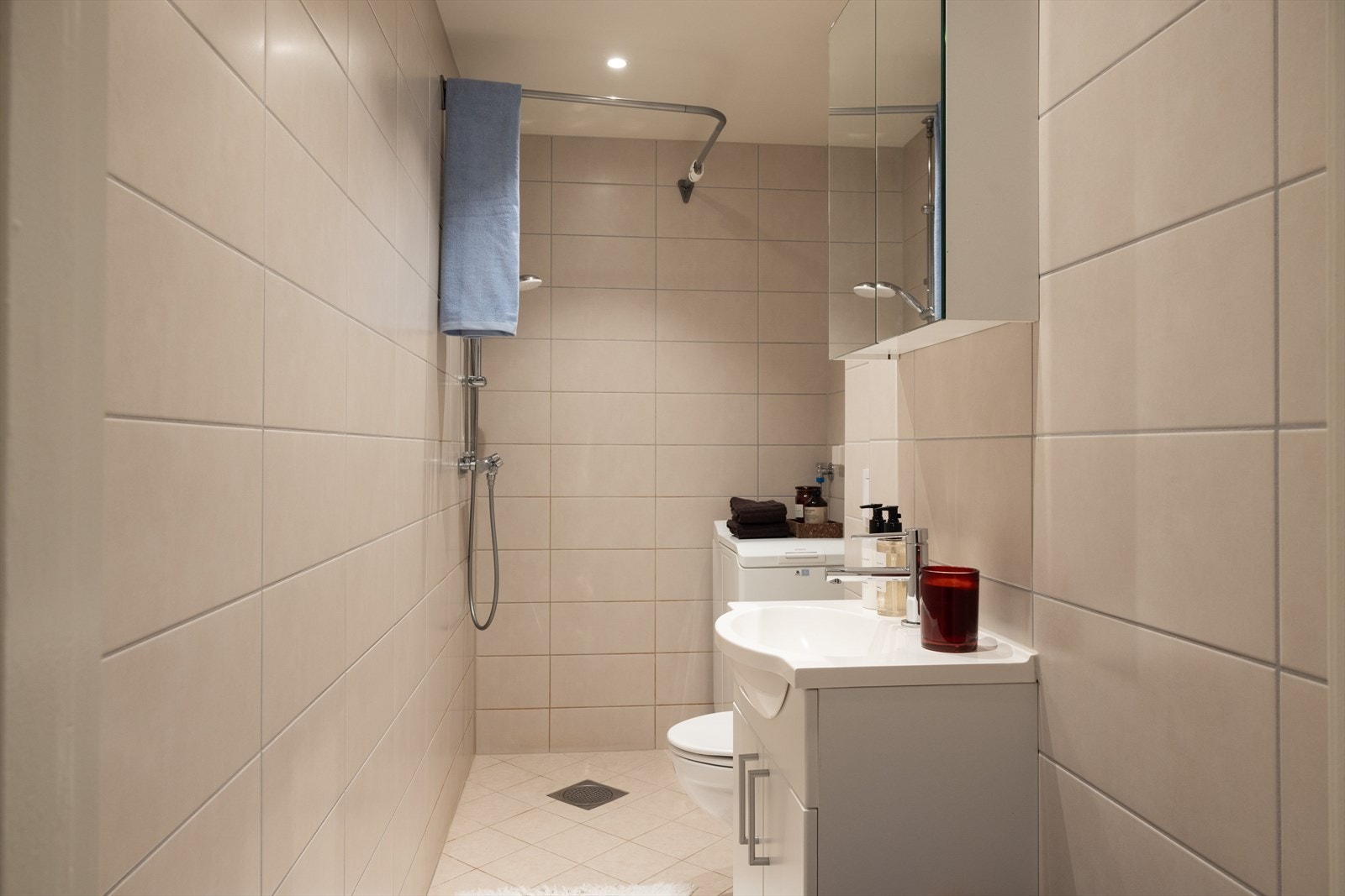 Badet inneholder baderomsinnredning med skap, servant og speilskap, veggmontert toalett samt dusjhjørne Galleribilde