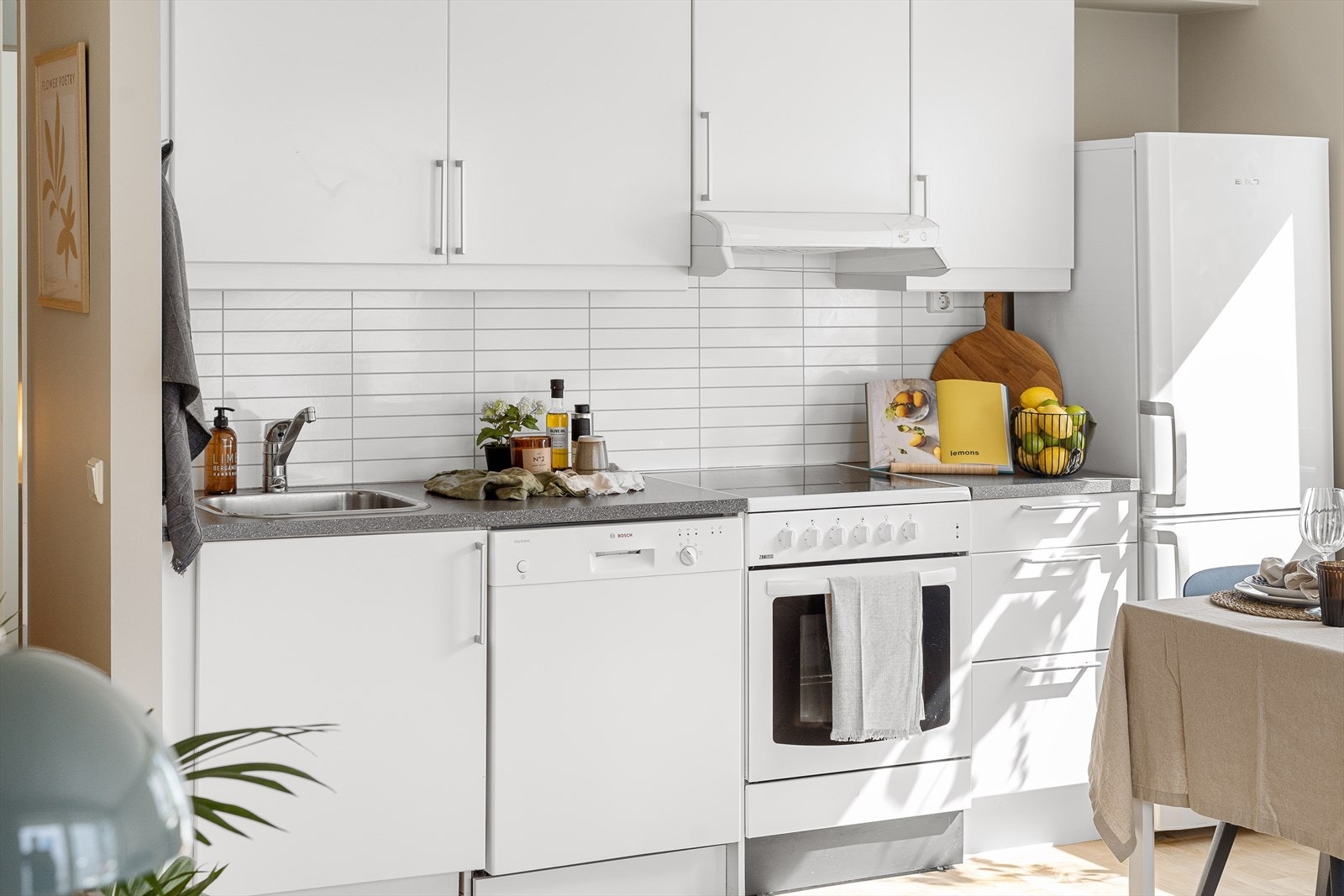 Effektiv innredning med stekeovn, kombiskap kjøl-frys, oppvaskmaskin og mekanisk avtrekksvifte over platetopp Galleribilde