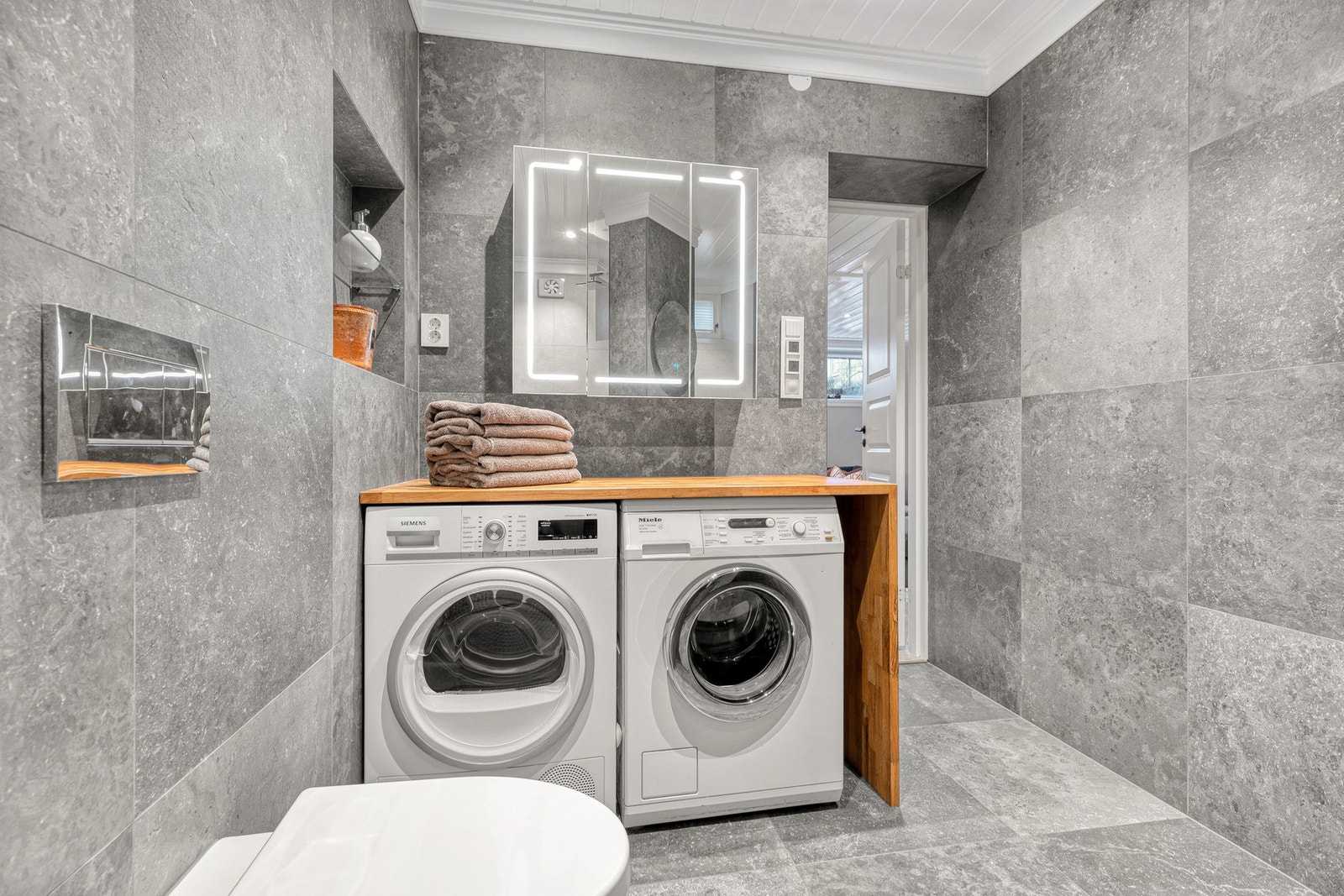 Under en benkeplate i tre er det sørget for opplegg for vaskemaskin/tørk. Galleribilde